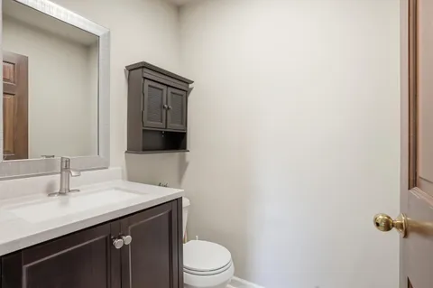 a bathroom with a granite countertop sink toilet and mirror