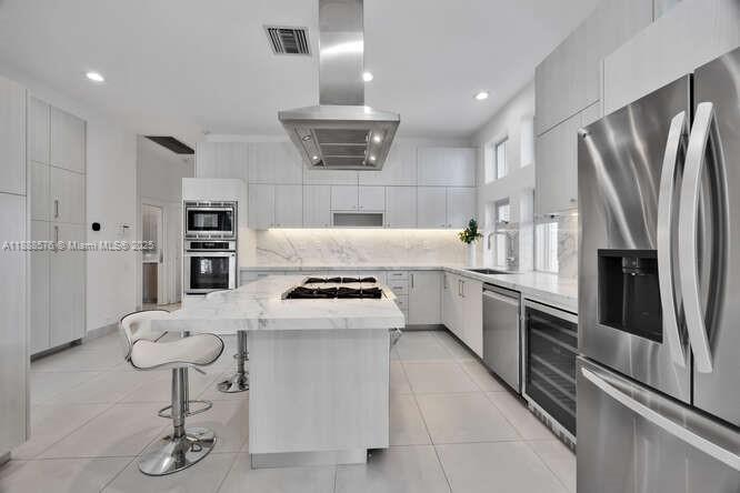 621 North Mashta Drive Key Biscayne, FL 33149 - Photo 11 of 34 a kitchen with stainless steel appliances kitchen island granite countertop a refrigerator a sink and a stove