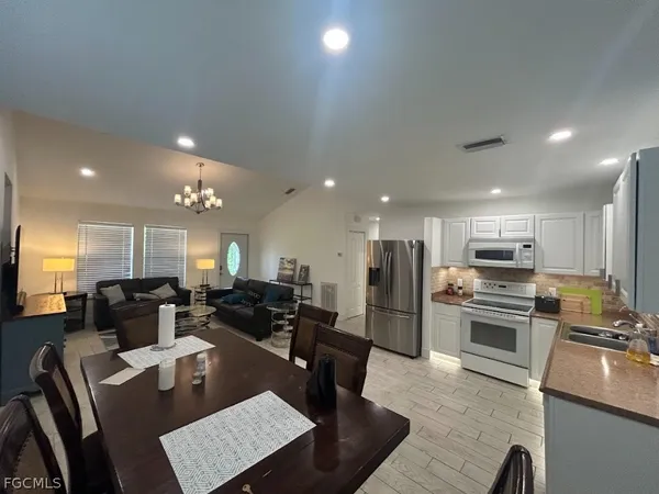 a kitchen with stainless steel appliances kitchen island granite countertop a refrigerator a stove a microwave oven a sink with island and chairs