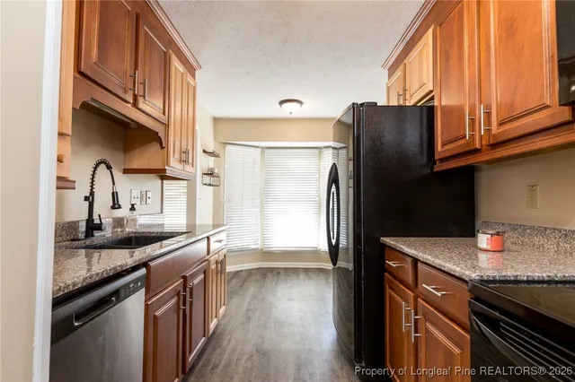 an empty room with wooden floor a ceiling fan a fireplace and windows