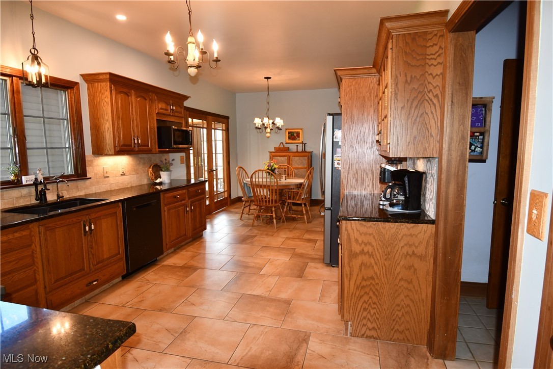 3180 West Calla Road Canfield, OH 44406 - Photo 12 of 49 Kitchen featuring tasteful backsplash, a notable chandelier, brown cabinets, appliances with stainless steel finishes, and a sink