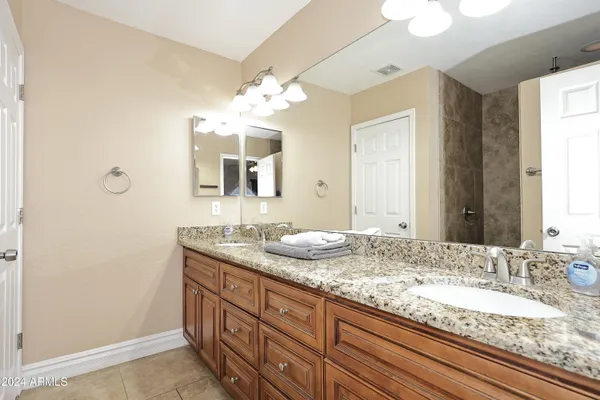 a bathroom with a granite countertop double vanity sink and a mirror