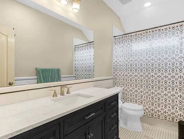 a bathroom with a granite countertop sink a toilet and a mirror