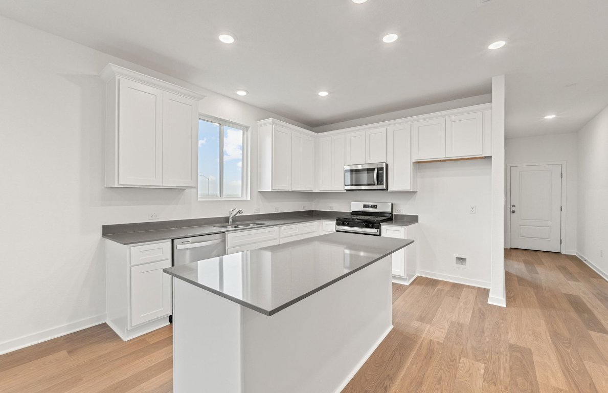 325 Sullivan Way Elgin, TX 78621 - Photo 5 of 19 a kitchen with a sink a stove a refrigerator and white cabinets