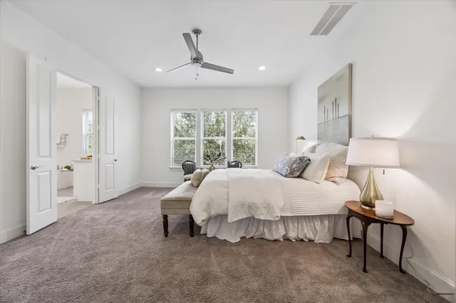 a bed sitting in a spacious bedroom next to a window and a lamp