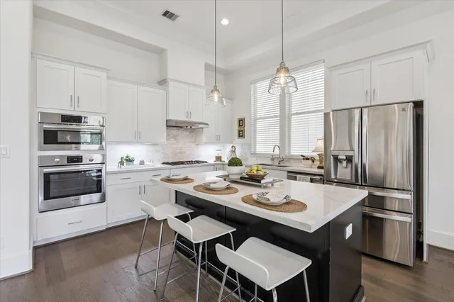 a kitchen with a stove a sink a kitchen island and stainless steel appliances