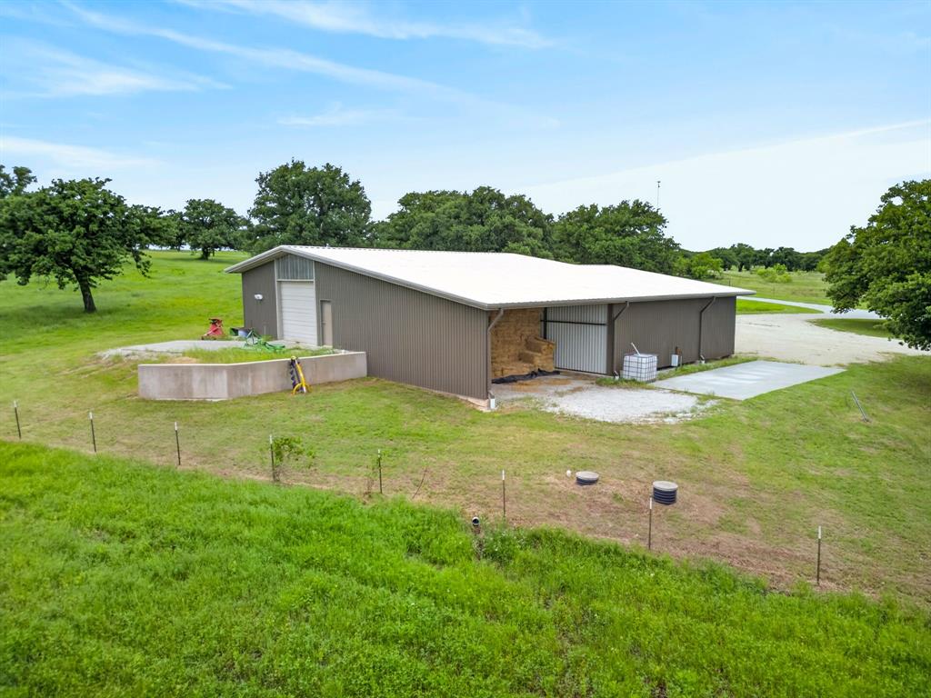 1080 North Greenbrier Road Nocona, TX 76255 - Photo 31 of 40 Expansive metal building featuring a white pitched roof, two large bay doors, and a covered open-air storage area