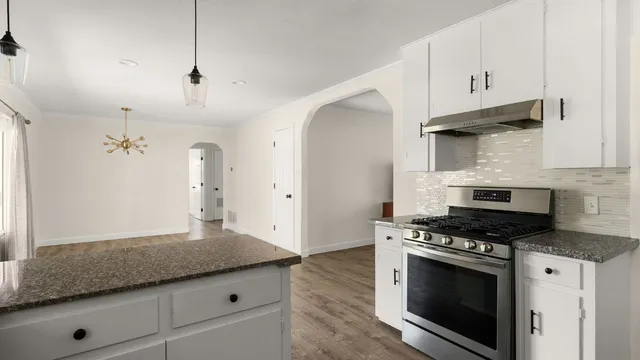 a kitchen with granite countertop stainless steel appliances a stove cabinets and wooden floor