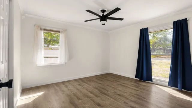 an empty room with a window and a ceiling fan
