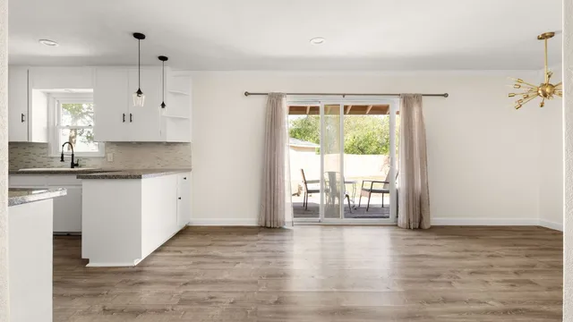a kitchen with granite countertop a stove a sink and white cabinets with wooden floor