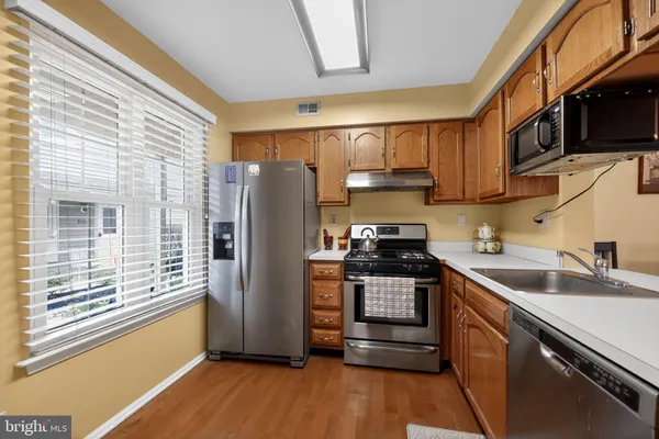 a kitchen with stainless steel appliances granite countertop a refrigerator a stove a sink and a microwave