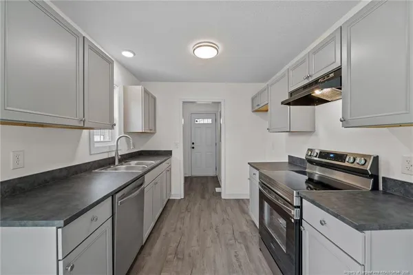 a kitchen with granite countertop a sink a stove and cabinets
