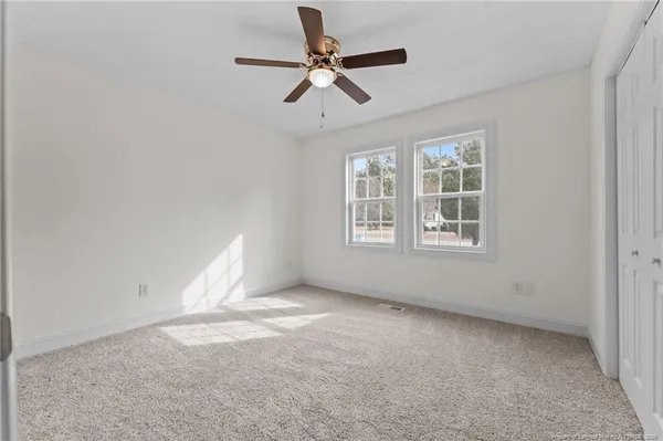 an empty room with closet and a chandelier fan