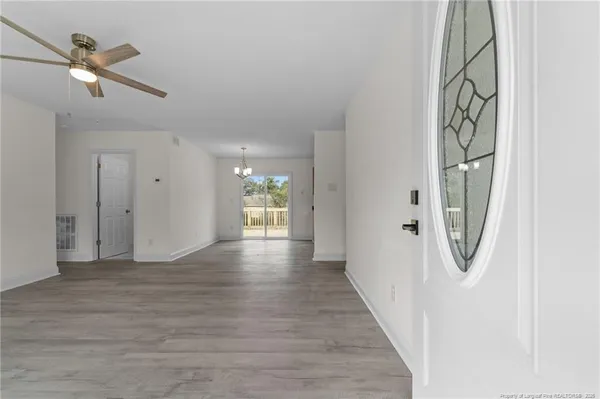 a view of an empty room with wooden floor and a window
