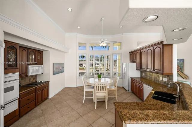 a kitchen with stainless steel appliances kitchen island granite countertop a table chairs and a refrigerator