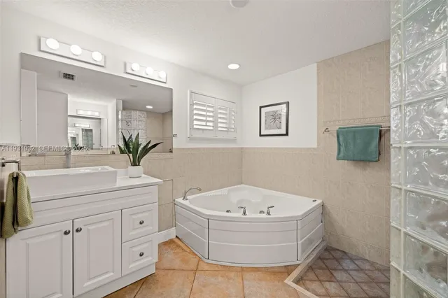 a bedroom with a bed a mirror on dresser and a flat screen tv