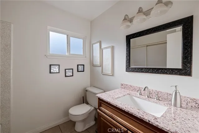 a bathroom with a granite countertop toilet sink and mirror