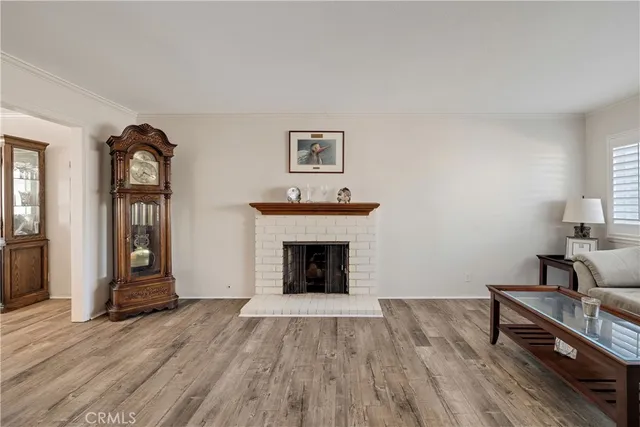 a view of an empty room with wooden floor fireplace and a window