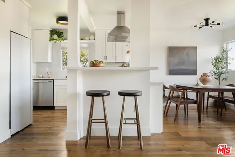 a kitchen with stainless steel appliances granite countertop a table chairs and a refrigerator