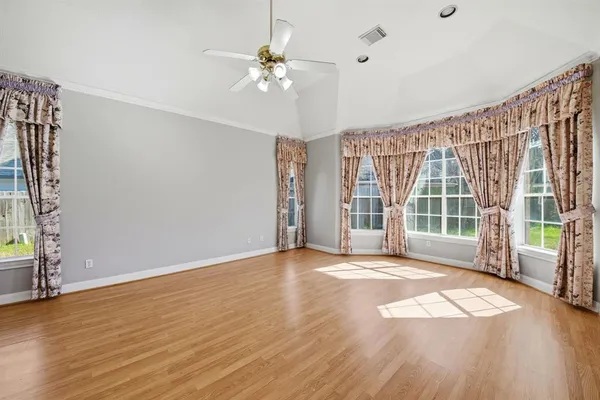 a view of an empty room with a window and wooden floor