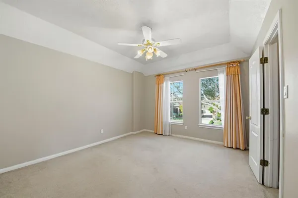 an empty room with chandelier fan and windows