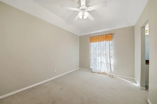 an empty room with a chandelier fan and windows