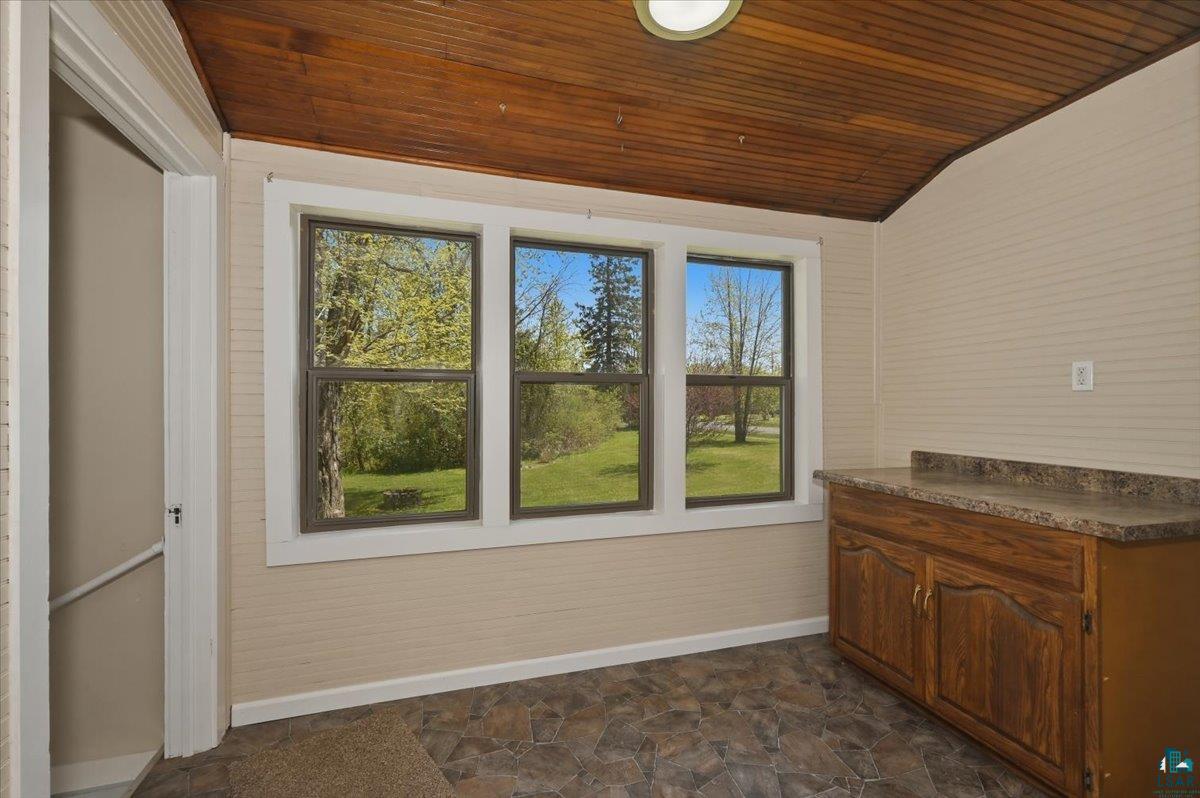 5319 East 3rd Street Superior, WI 54880 - Photo 9 of 33 Room with three windows, wood-finish ceiling, stone-look floor tiles, beadboard walls, and built-in cabinetry with a countertop
