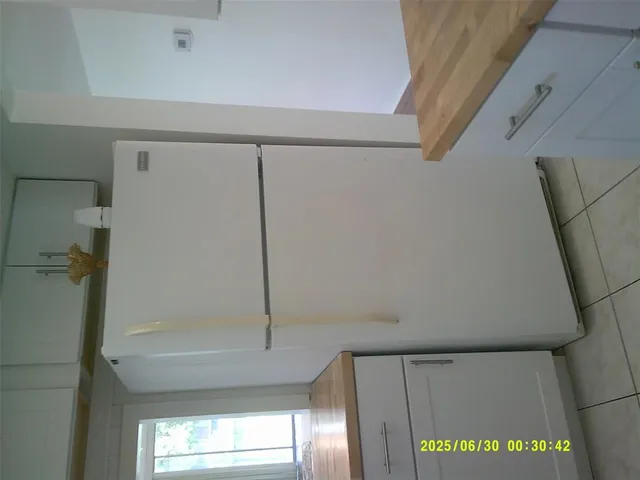 a view of a refrigerator in kitchen and cabinets