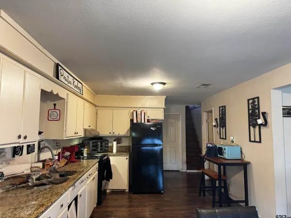 a kitchen with stainless steel appliances granite countertop a refrigerator stove microwave and wooden floor