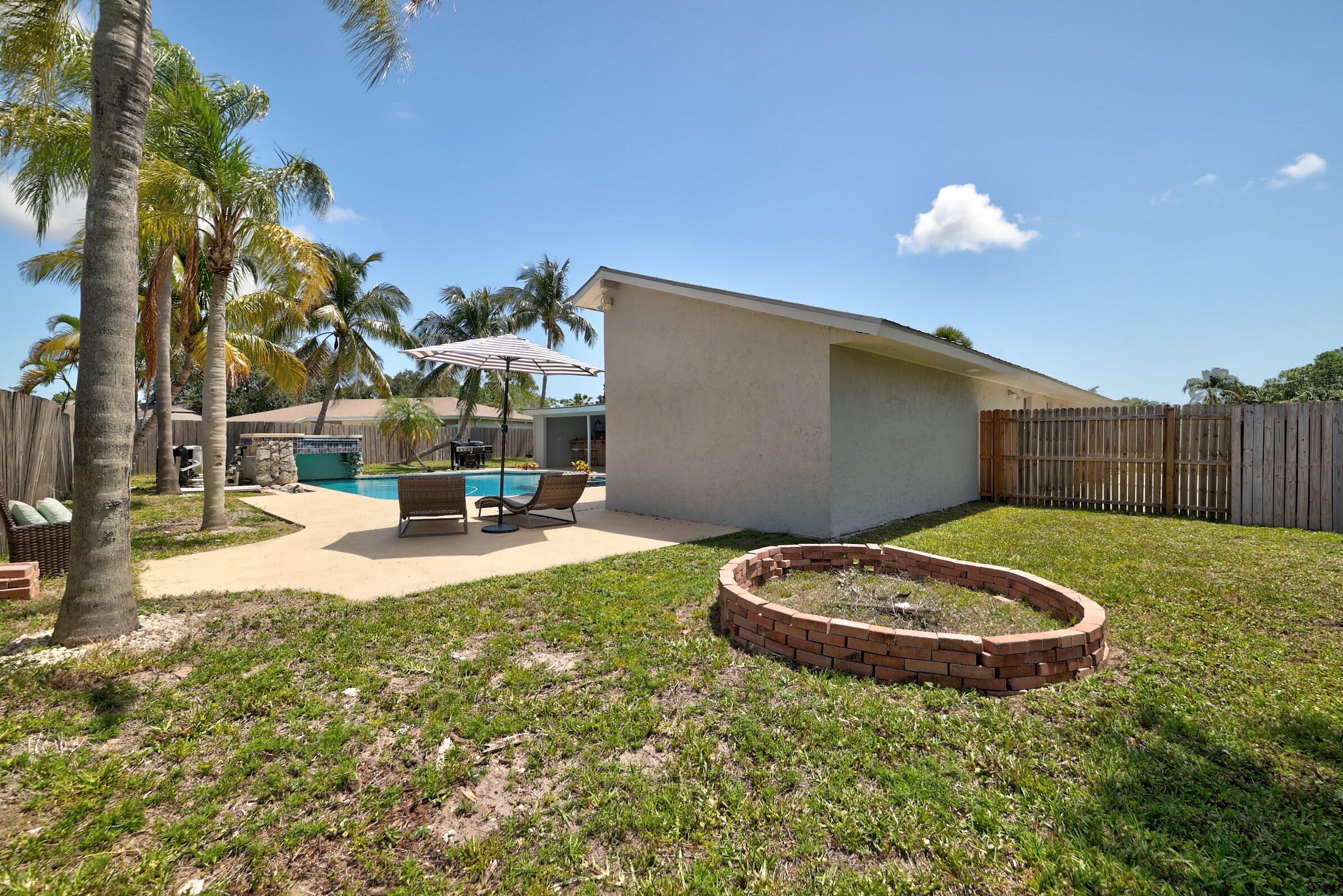 2068 Southeast Triumph Road Port St. Lucie, FL 34952 - Photo 41 of 59 a view of a backyard with table and chairs a fire pit and potted plants