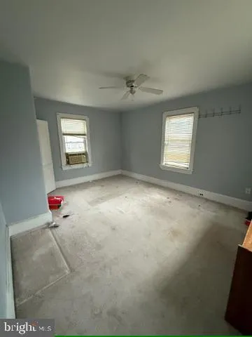 an empty room with windows and ceiling fan