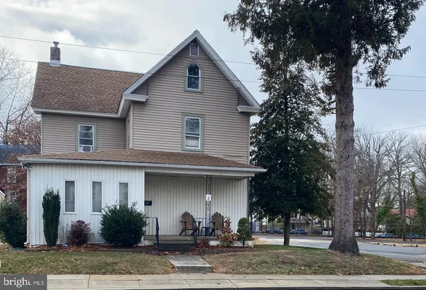 a front view of a house with trees and plants
