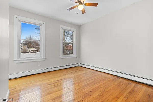 a view of empty room with wooden floor and fan