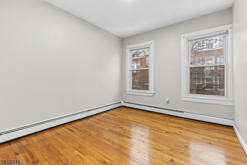 336 Madison Avenue, Unit 2 Newark, NJ 07108 - Photo 6 of 11 an empty room with wooden floor and windows