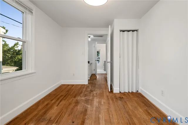 an empty room with wooden floor and windows