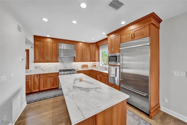 a kitchen with granite countertop a refrigerator and a stove top oven