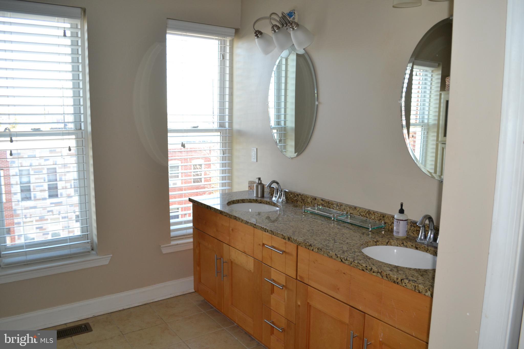 1410 North Bond Street Baltimore, MD 21213 - Photo 18 of 26 a bathroom with a granite countertop double vanity sink a mirror and a window