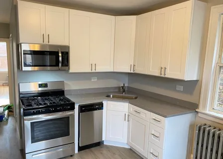 a kitchen with granite countertop white cabinets and stainless steel appliances