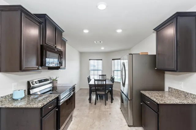 a kitchen with granite countertop stainless steel appliances a refrigerator microwave and stove top oven