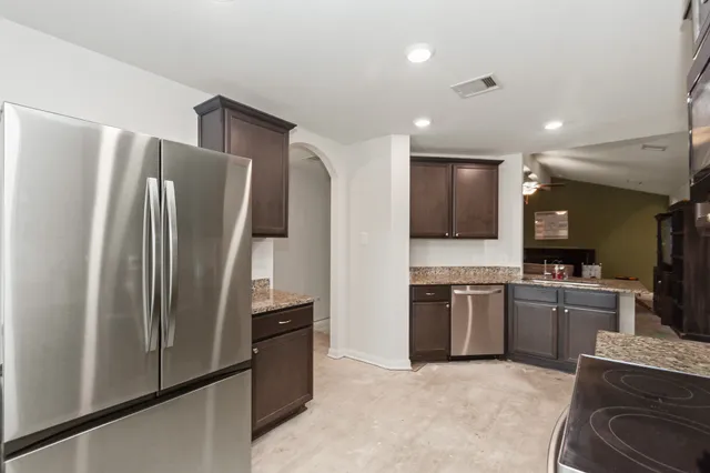 a kitchen with stainless steel appliances granite countertop a refrigerator and a stove top oven