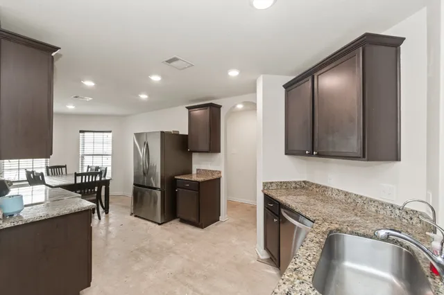 a kitchen with stainless steel appliances granite countertop a sink a stove and a refrigerator