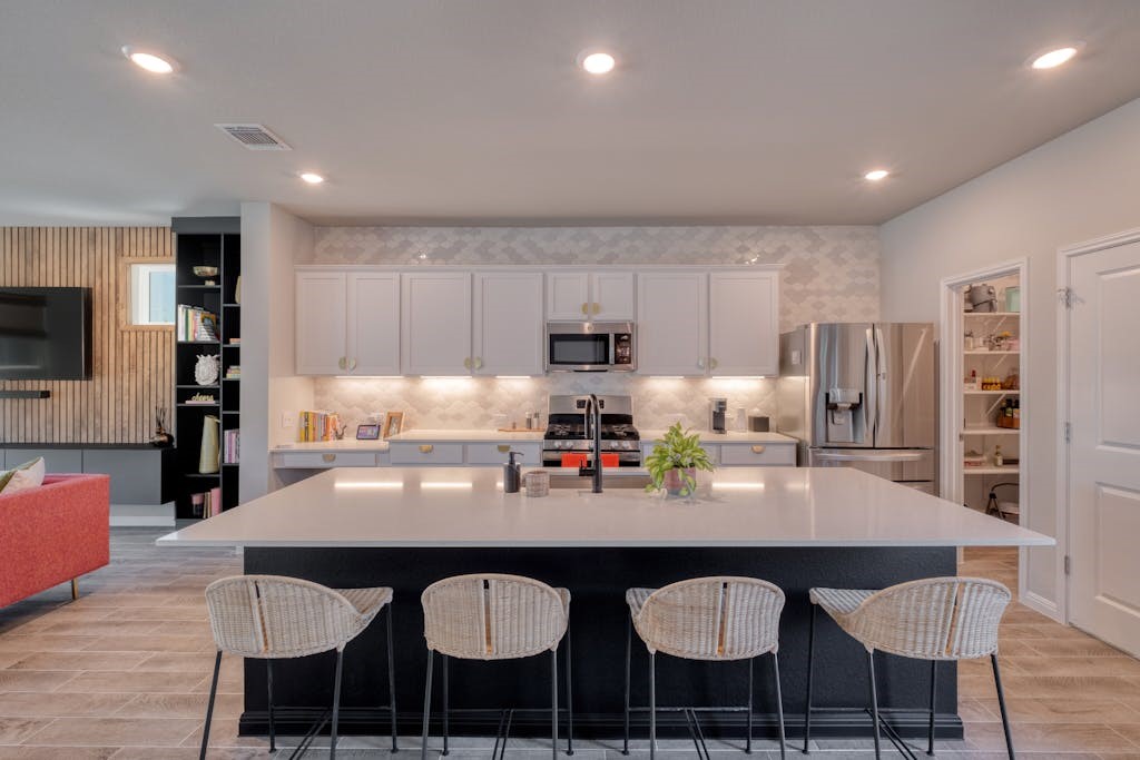a kitchen with granite countertop a dining table chairs cabinets and stainless steel appliances