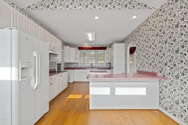 a kitchen with stainless steel appliances granite countertop a refrigerator a oven and white cabinets with wooden floor