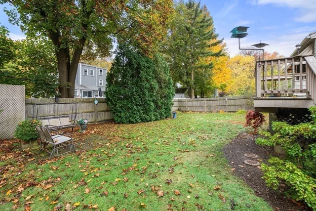 a backyard of a house with table and chairs plants and large trees