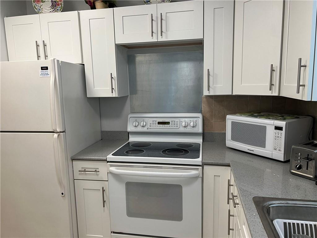 2100 Northeast 38th Street, Unit 124 Lighthouse Point, FL 33064 - Photo 1 of 30 a kitchen with stainless steel appliances a stove a microwave and a refrigerator