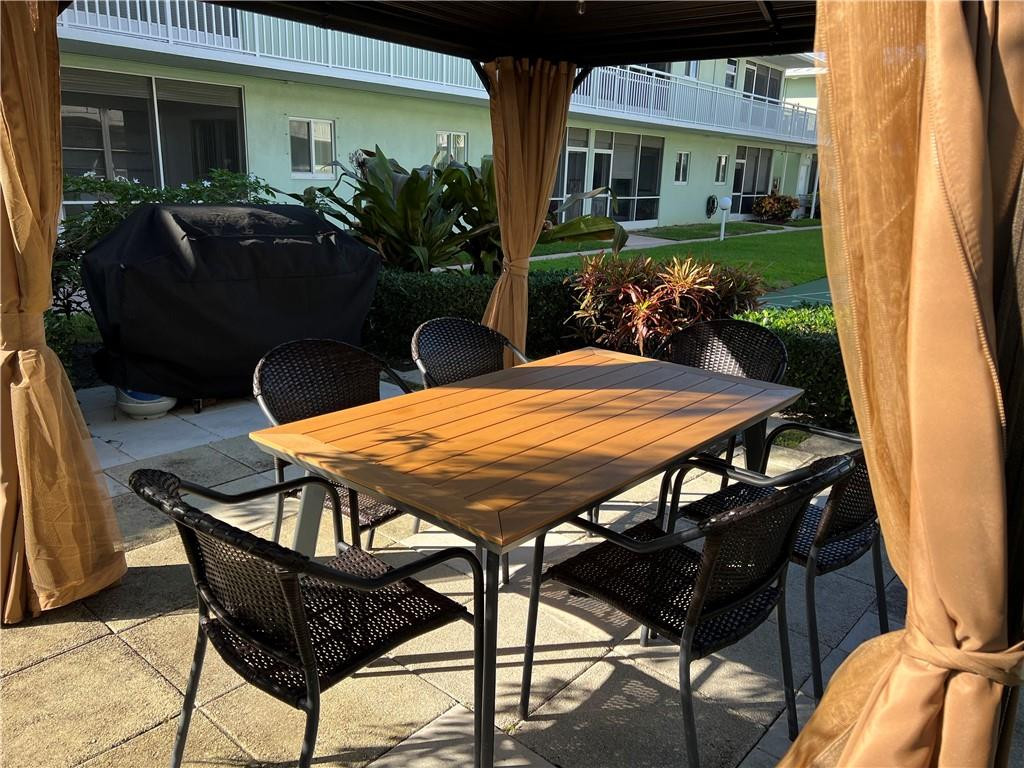 2100 Northeast 38th Street, Unit 124 Lighthouse Point, FL 33064 - Photo 14 of 30 a view of a patio with table and chairs potted plants with wooden floor