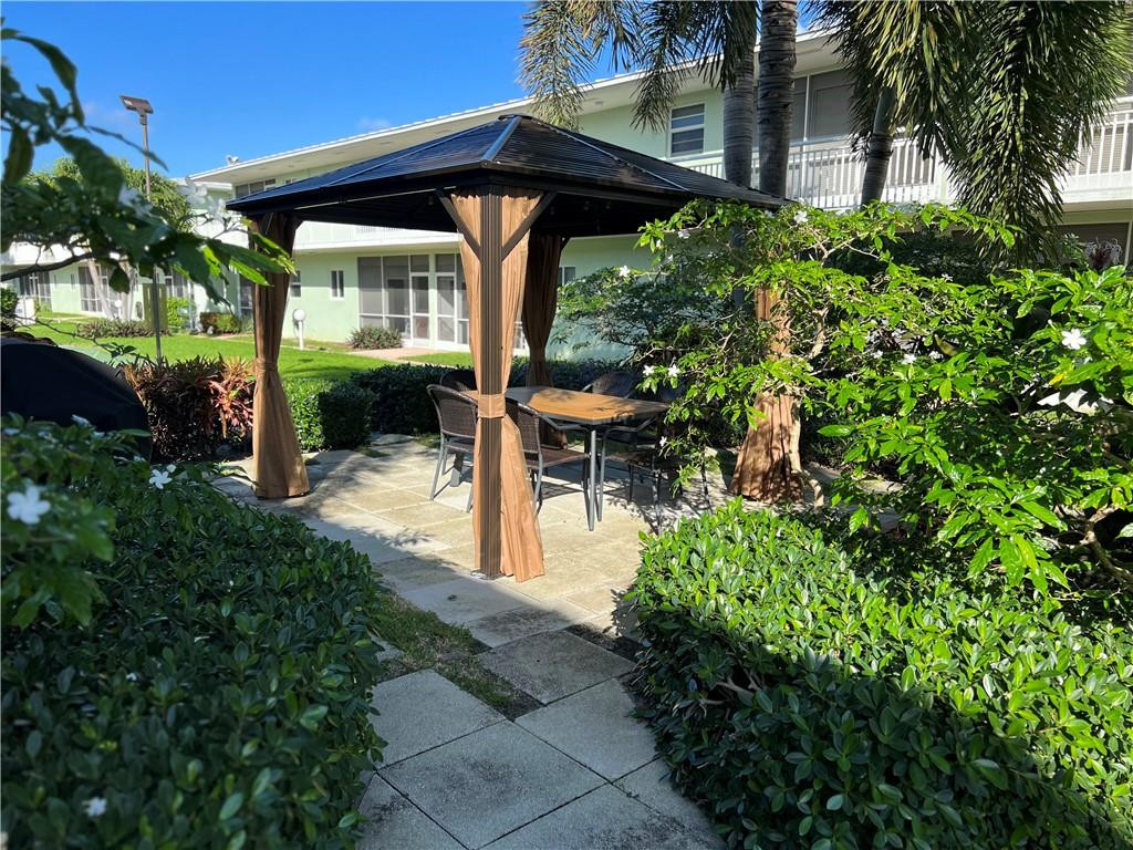 2100 Northeast 38th Street, Unit 124 Lighthouse Point, FL 33064 - Photo 17 of 30 a view of a patio with table and chairs potted plants and large tree