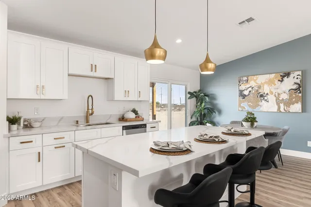 a kitchen with stainless steel appliances kitchen island granite countertop a sink a stove a dining table and chairs