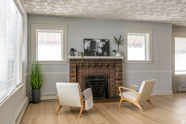 33 North 200 East Logan, UT 84321 - Photo 8 of 54 Sitting room featuring a baseboard radiator, wood finished floors, baseboard heating, and a brick fireplace
