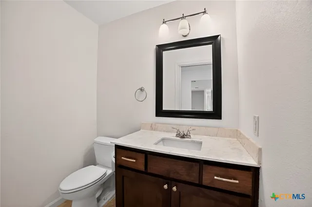 a bathroom with a toilet a sink a vanity and mirror
